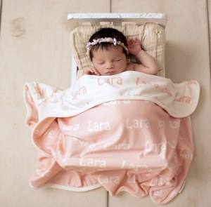 imagem de bebê reborn coberto por uma manta personalizad