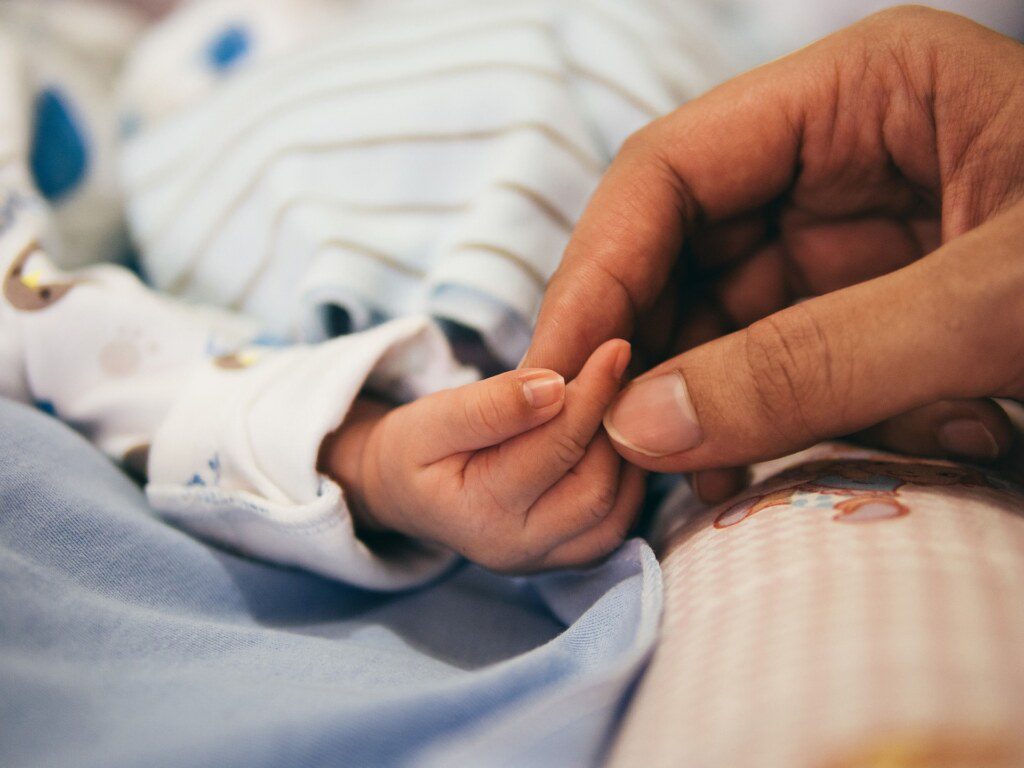 A mão de um recém nascido com um adulto
