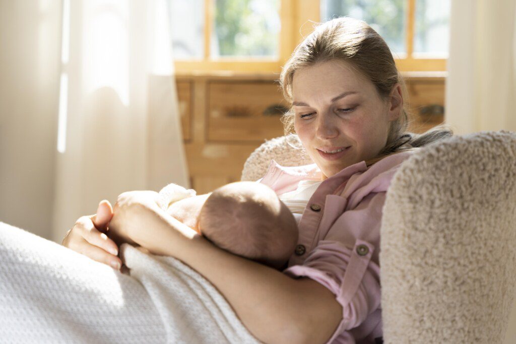 mulher olhando e segurando um bebê recém-nascido no colo