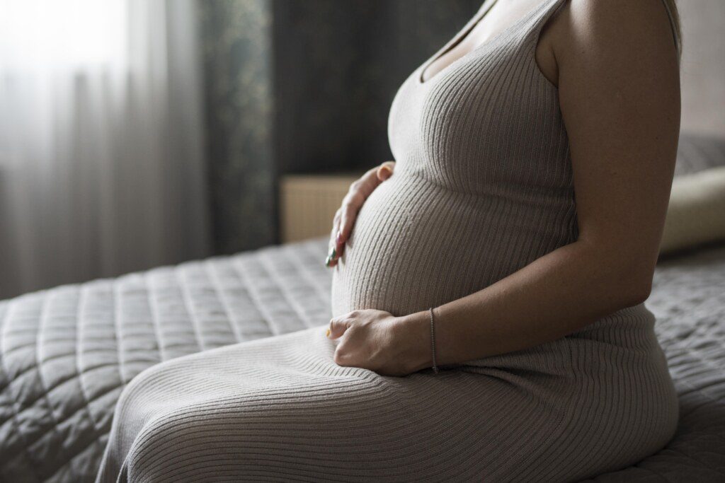 Mulher grávida sentada com as mãos na barriga