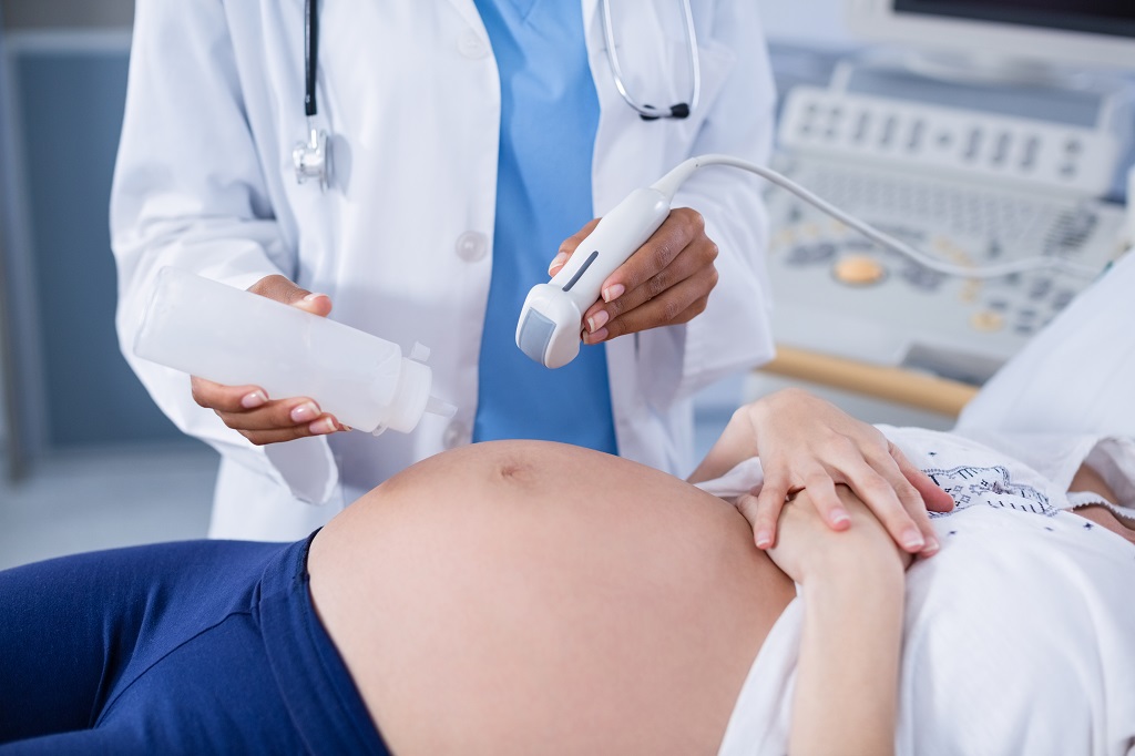 uma mulher grávida deitada faz exame pré nata de ultrasonografia