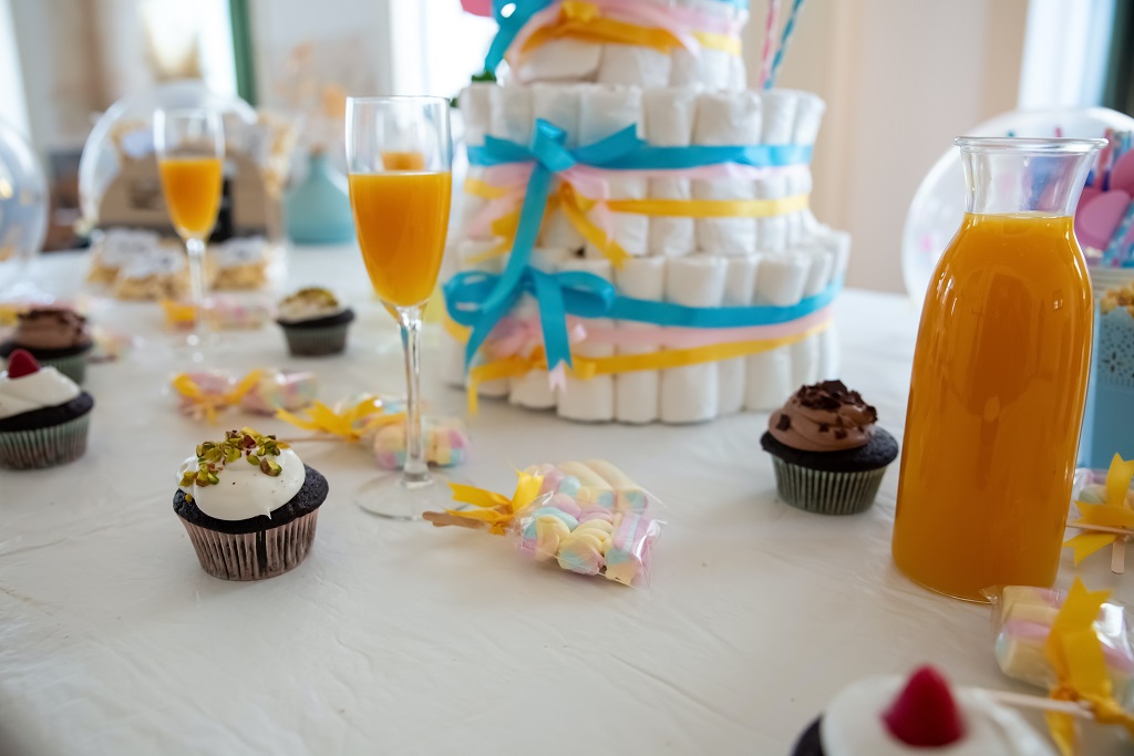 uma mesa decorada para um chá de bebê com fraldas em formato de bolo e taças com suco de laranja