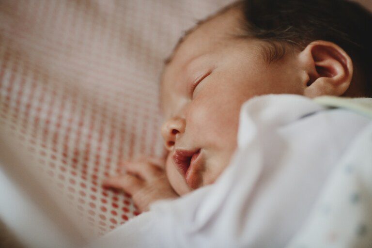 Um bebê recém-nascido está dormindo em uma cama