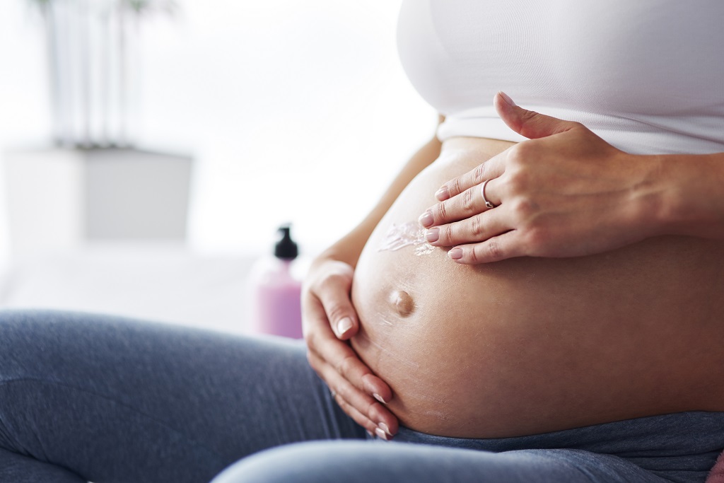 Uma mulher grávida com as mãos na barriga