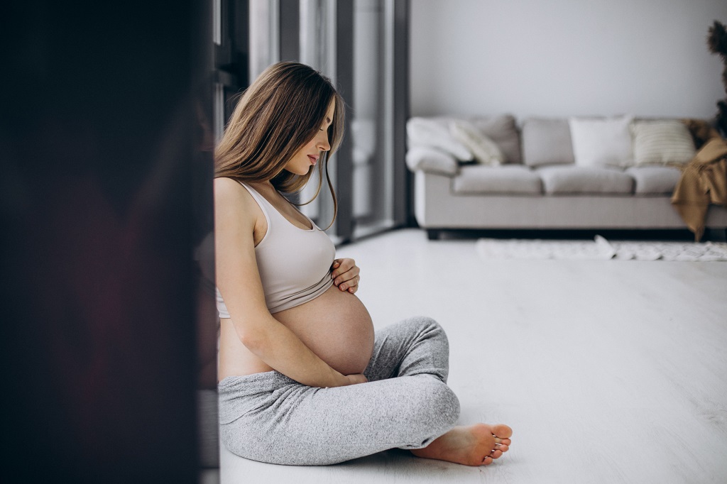 Uma mulher gravida sentada segurando a barriga
